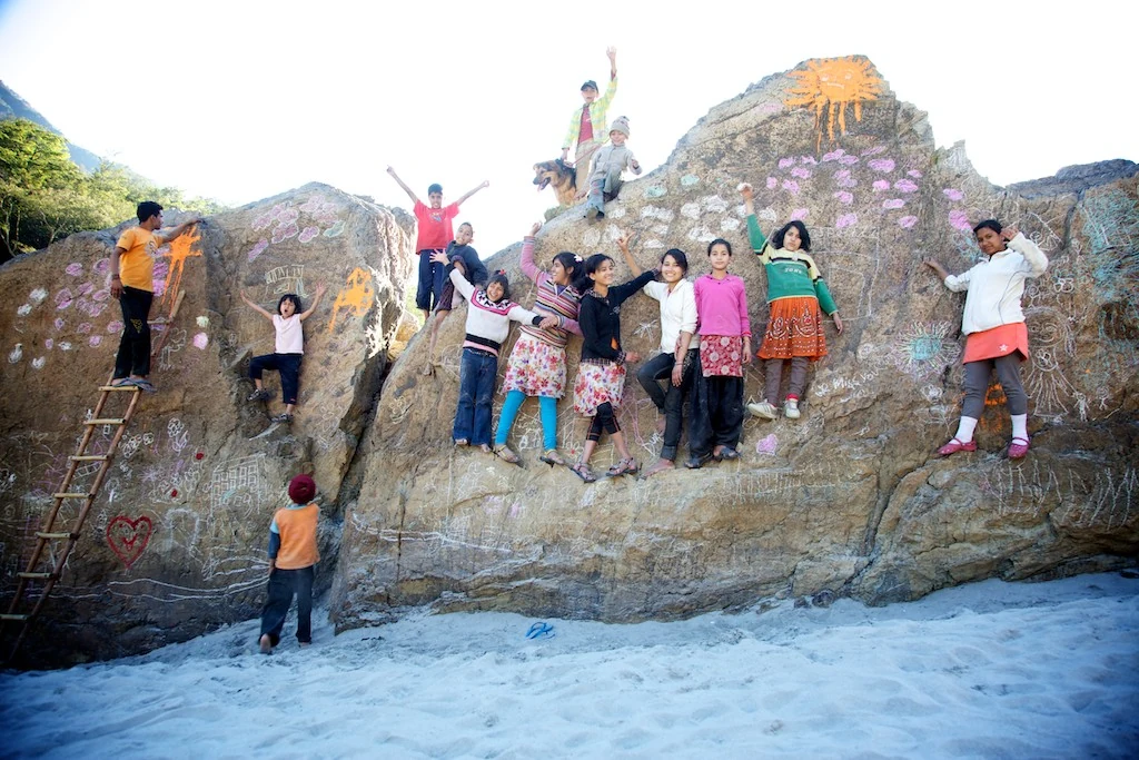 Children gathered on rocks covered with colourful drawings during The Ideal City Project.