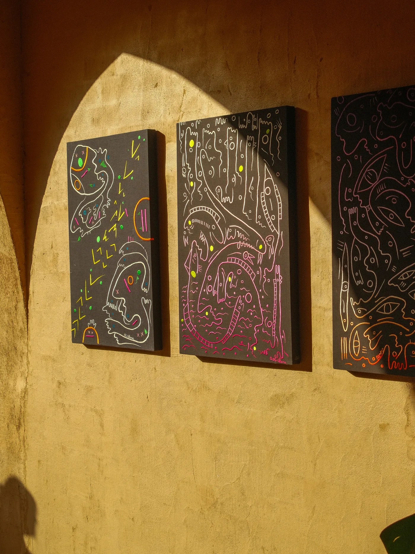 Three embroidered paintings on a sunlit wall at Nômade Temple