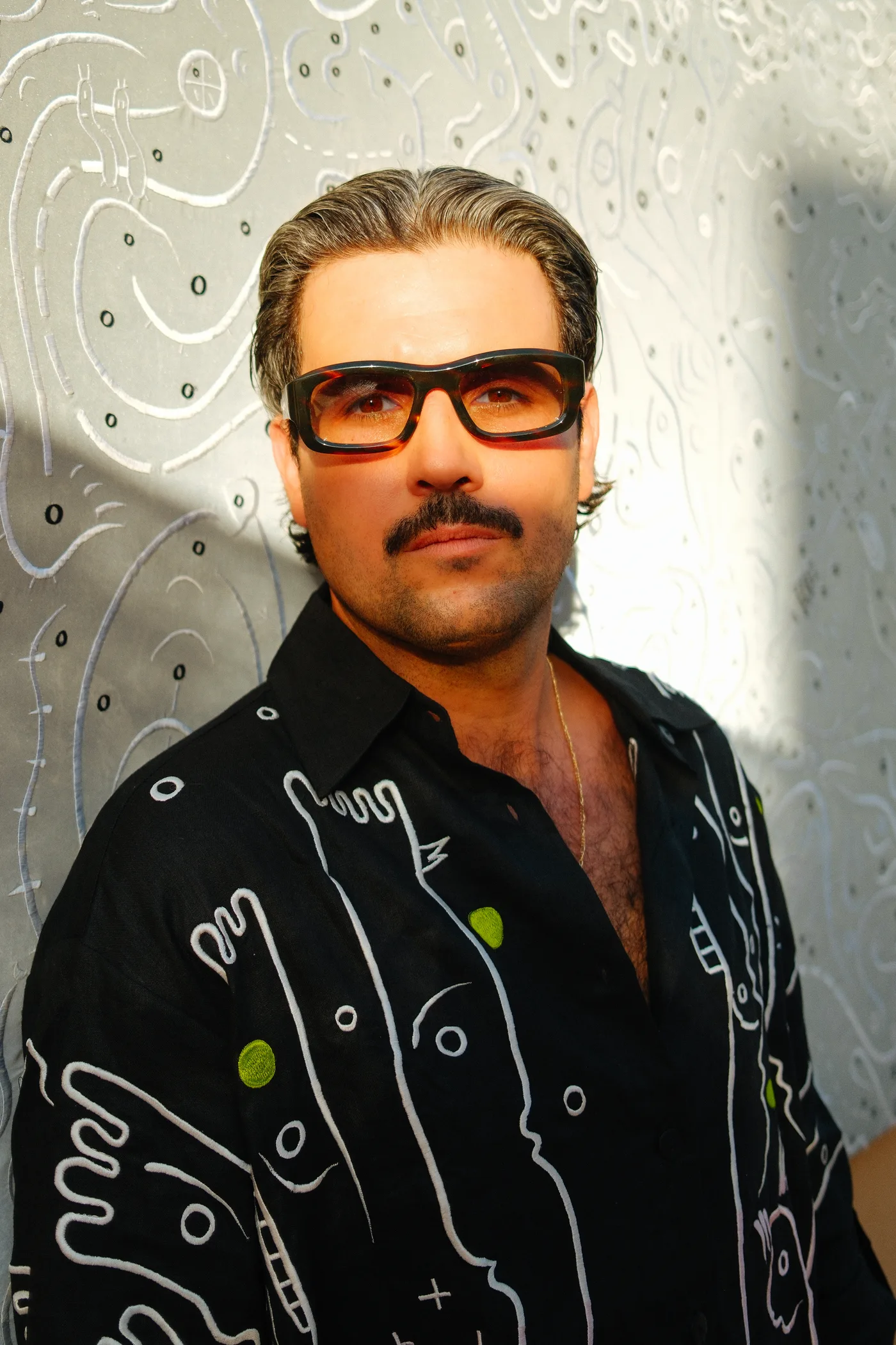 Ole Ukena wearing a drawn-pattern shirt in front of reflective embroidery